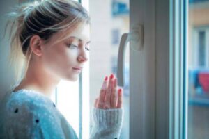 Woman looks out the window as she considers an opioid addiction treatment program for women 