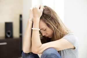 Woman sits on floor in agony considering cocaine addiction treatment