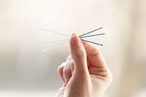 Person holds acupuncture needles to represent acupuncture therapy in North Carolina 