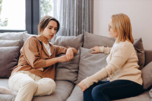 Two women sit on couch and discuss women's dual diagnosis treatment center