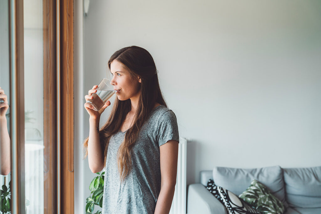Woman drinks a glass of water while wondering if edibles are addictive