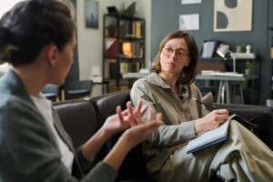 Woman sits on couch and talks to trusted friend about bipolar disorder treatment