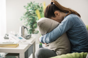 Woman hugs pillow as she struggles, wondering how to know if you need therapy​